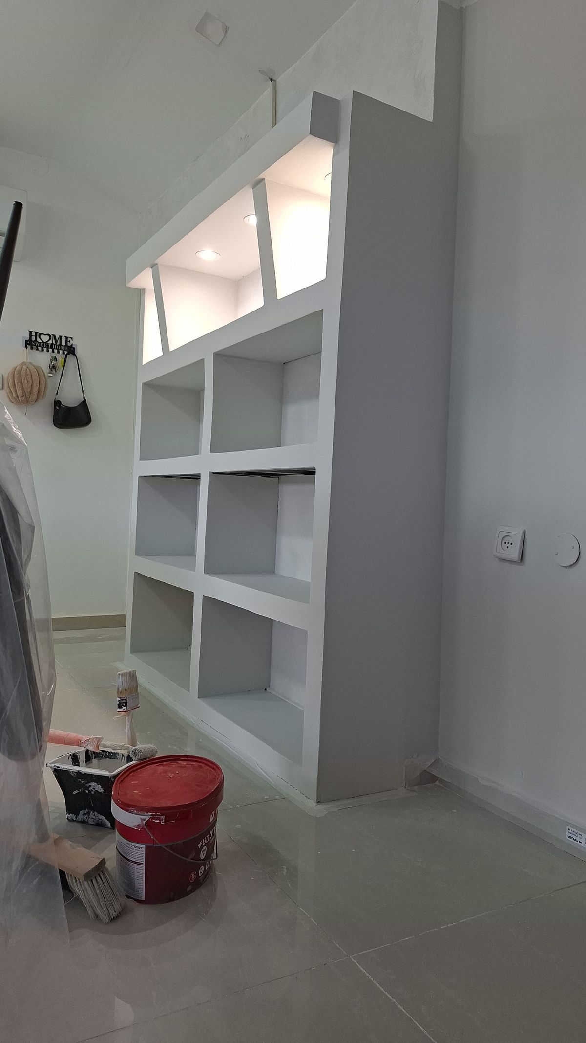 ארון אחסון לבן עם מדפים ותאורה, בתהליך בנייה